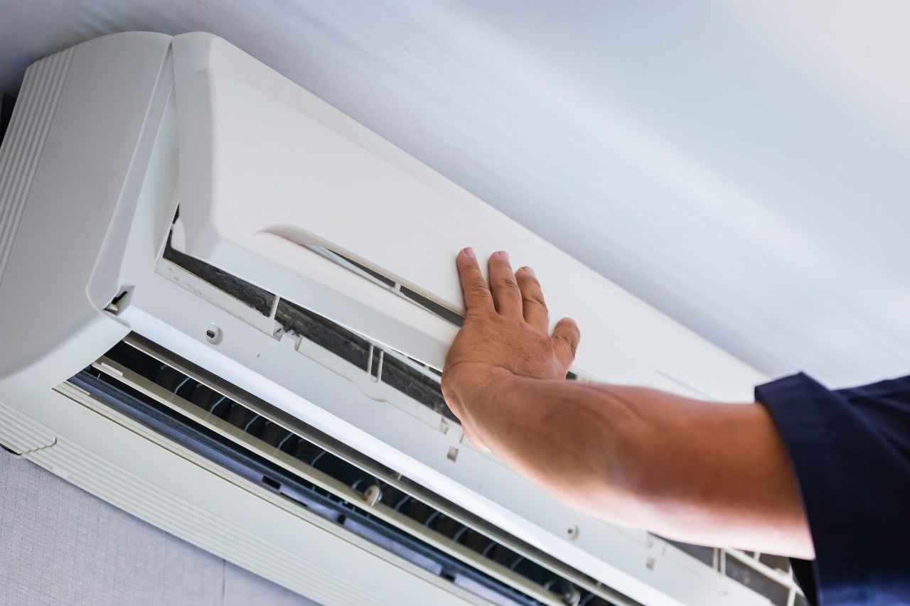 Professional technician servicing a wall-mounted split air conditioning unit during routine maintenance.